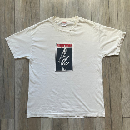 Supreme SS05 STAX Records White Gun Tee is a white short-sleeve T-shirt from the Spring/Summer 2005 collection. The front features a modified Stax Records-inspired logo with “Supreme” in red and a hand holding a gun graphic. This piece is super rare.