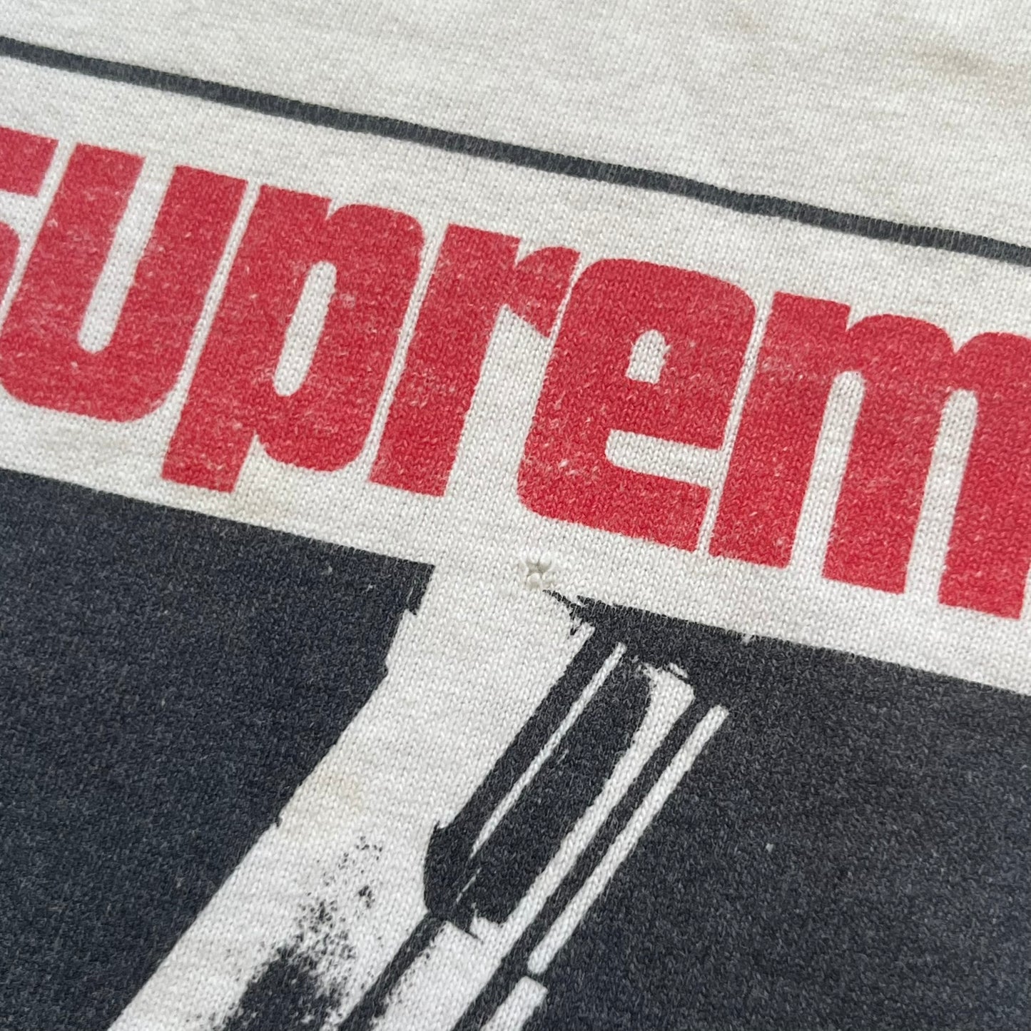 Supreme SS05 STAX Records White Gun Tee is a white short-sleeve T-shirt from the Spring/Summer 2005 collection. The front features a modified Stax Records-inspired logo with “Supreme” in red and a hand holding a gun graphic. This piece is super rare.