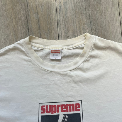 Supreme SS05 STAX Records White Gun Tee is a white short-sleeve T-shirt from the Spring/Summer 2005 collection. The front features a modified Stax Records-inspired logo with “Supreme” in red and a hand holding a gun graphic. This piece is super rare.