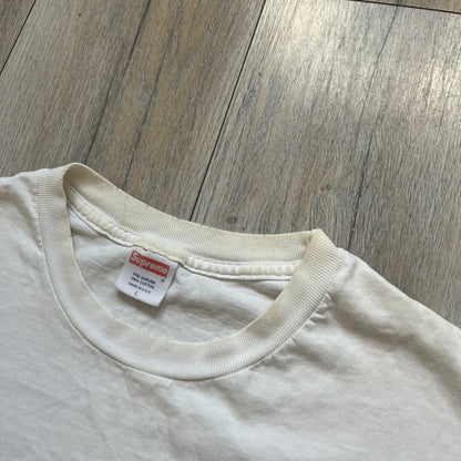 Supreme SS05 STAX Records White Gun Tee is a white short-sleeve T-shirt from the Spring/Summer 2005 collection. The front features a modified Stax Records-inspired logo with “Supreme” in red and a hand holding a gun graphic. This piece is super rare.
