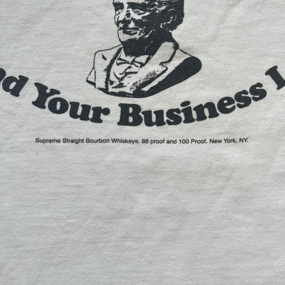 Supreme SS11 Mind Your Business White Tee is a white short-sleeve T-shirt from the Spring/Summer 2011 collection, made in the USA. The front features a graphic inspired by a whiskey label, including an old Supreme logo, a bust of an older man, a small “Mind Your Business” figure, and text referencing Supreme Bourbon Whiskeys with a New York address. This design is part of Supreme’s second delivery of SS11 T-shirts.