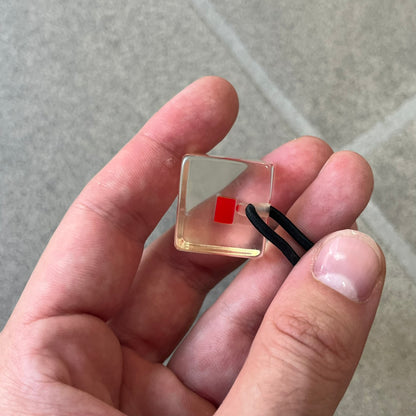 Supreme SS18 Hair Bobbles (Set of 2) features clear acrylic dice-shaped pieces with small red Supreme Box Logo details inside, attached to black elastic bands. The set includes two hair bobbles and comes in the original white Supreme box. Released on May 17, 2018.
