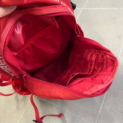Supreme SS18 Red Backpack features a red construction with a large main compartment suitable for laptops and other larger devices, along with a front zippered pocket for smaller items. It has dual side mesh pockets and a Supreme Box Logo on the front.
