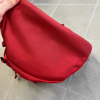Supreme SS18 Red Backpack features a red construction with a large main compartment suitable for laptops and other larger devices, along with a front zippered pocket for smaller items. It has dual side mesh pockets and a Supreme Box Logo on the front.
