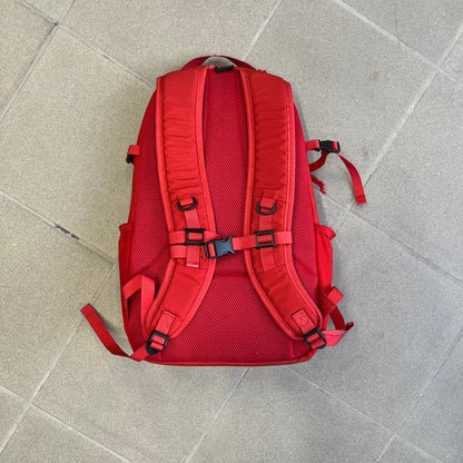 Supreme SS18 Red Backpack features a red construction with a large main compartment suitable for laptops and other larger devices, along with a front zippered pocket for smaller items. It has dual side mesh pockets and a Supreme Box Logo on the front.
