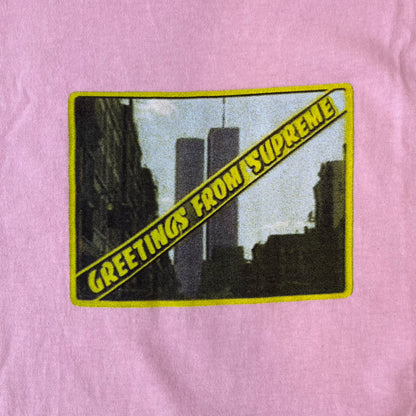 Supreme SS19 Greetings Pink Tee features a pink T-shirt with a front graphic designed as a greeting card showing the New York City skyline. The graphic includes the text “Greetings From Supreme” and depicts the original skyline with the Twin Towers. Released as part of Supreme’s Spring/Summer 2019 collection. Made in USA, 100% Cotton.
