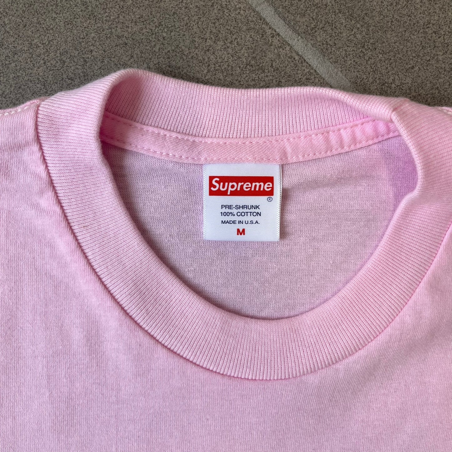Supreme SS19 Greetings Pink Tee features a pink T-shirt with a front graphic designed as a greeting card showing the New York City skyline. The graphic includes the text “Greetings From Supreme” and depicts the original skyline with the Twin Towers. Released as part of Supreme’s Spring/Summer 2019 collection. Made in USA, 100% Cotton.
