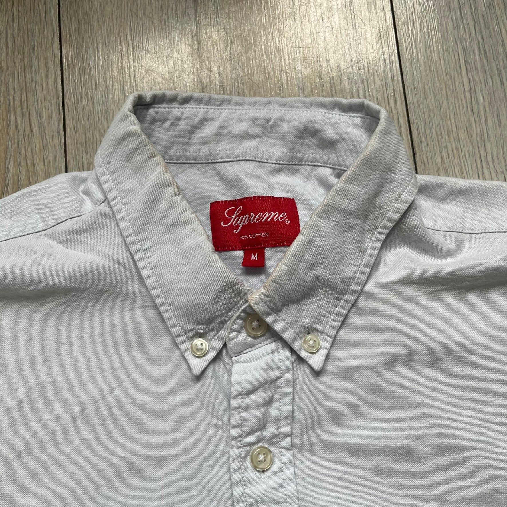 Supreme SS19 Oxford Shirt is a light blue button-up shirt from the Spring/Summer 2019 collection, released on February 21, 2019. It features a button-front closure, a standard collar, and a single chest pocket with a small Supreme tag attached to the side.
