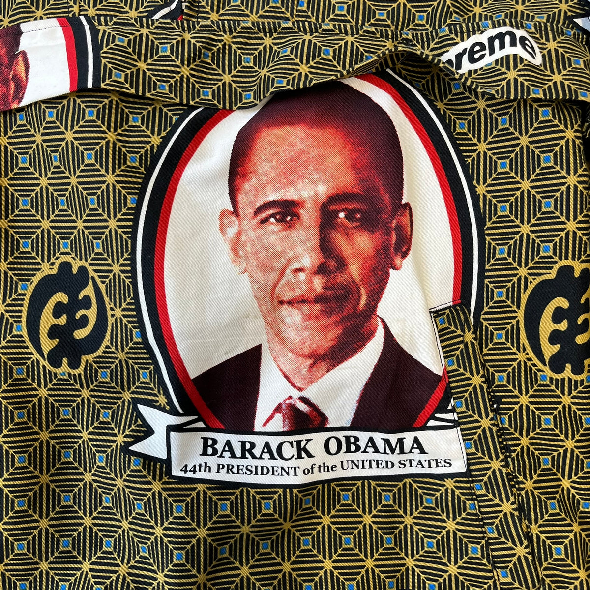 Supreme SS2017 Obama Green Anorak is a green/olive 100% cotton quarter-zip anorak with an all-over patchwork print incorporating Barack Obama’s face, the words “Barack Obama,” and scattered Supreme logos. The design pays homage to the “khanas,” vibrant patterned garments with political graphics made by local designers in Ghana to commemorate the former president’s 2009 visit. It has a drawstring hood and hem and lower front hand pockets.