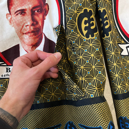 Supreme SS2017 Obama Green Anorak is a green/olive 100% cotton quarter-zip anorak with an all-over patchwork print incorporating Barack Obama’s face, the words “Barack Obama,” and scattered Supreme logos. The design pays homage to the “khanas,” vibrant patterned garments with political graphics made by local designers in Ghana to commemorate the former president’s 2009 visit. It has a drawstring hood and hem and lower front hand pockets.