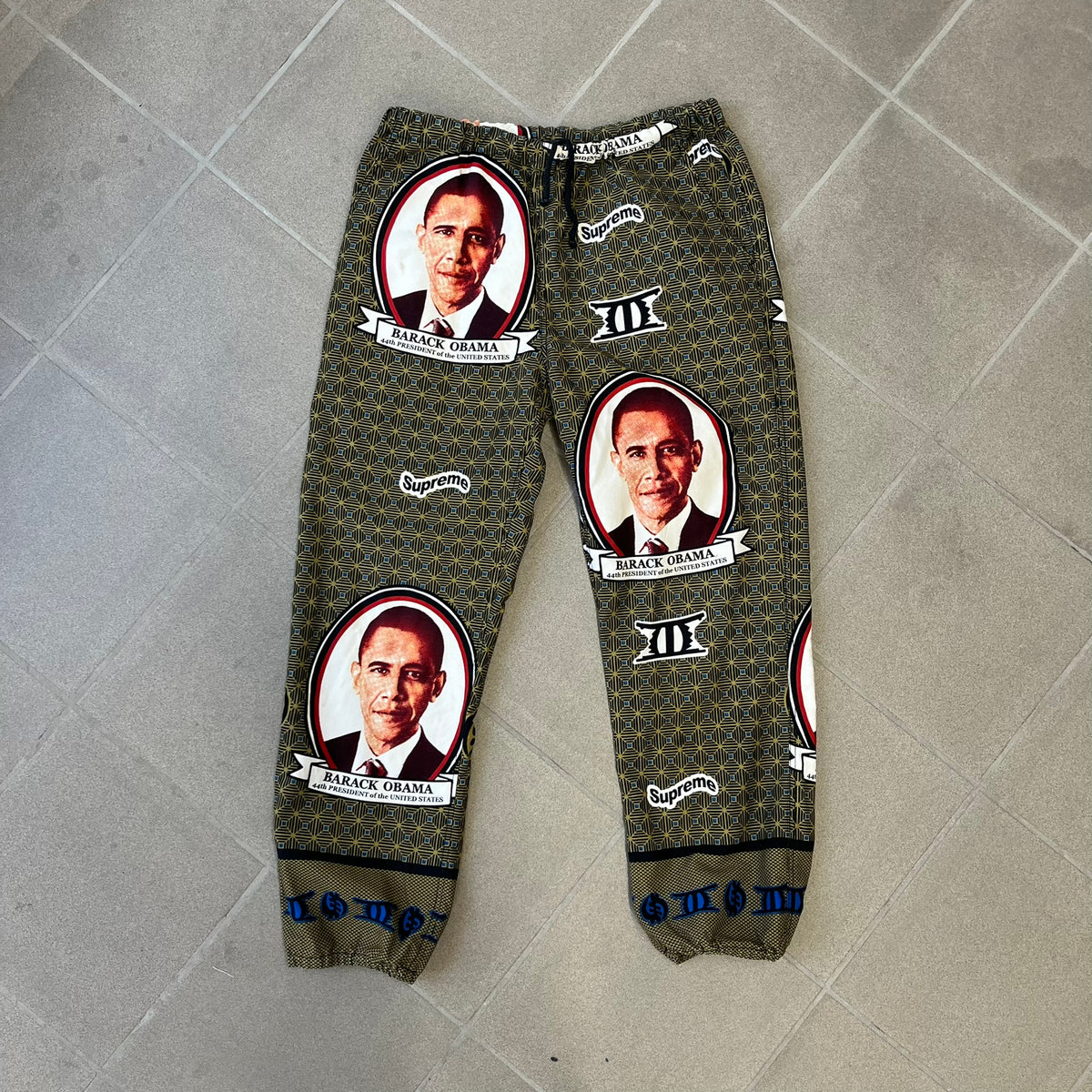Supreme SS2017 Obama Green Pants are green/olive pants with the all-over patchwork print incorporating Barack Obama’s face, the words “Barack Obama,” and scattered Supreme logos. The design pays homage to the “khanas,” vibrant patterned garments with political graphics made by local designers in Ghana to commemorate the former president’s 2009 visit. They have two front pockets and one back pocket.