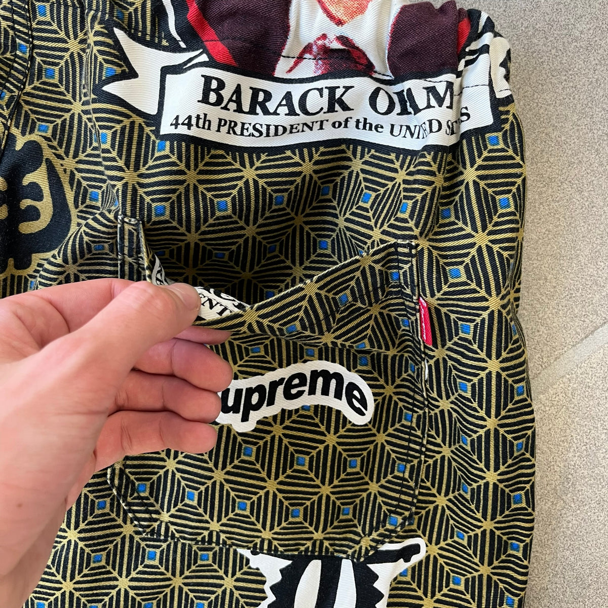 Supreme SS2017 Obama Green Pants are green/olive pants with the all-over patchwork print incorporating Barack Obama’s face, the words “Barack Obama,” and scattered Supreme logos. The design pays homage to the “khanas,” vibrant patterned garments with political graphics made by local designers in Ghana to commemorate the former president’s 2009 visit. They have two front pockets and one back pocket.