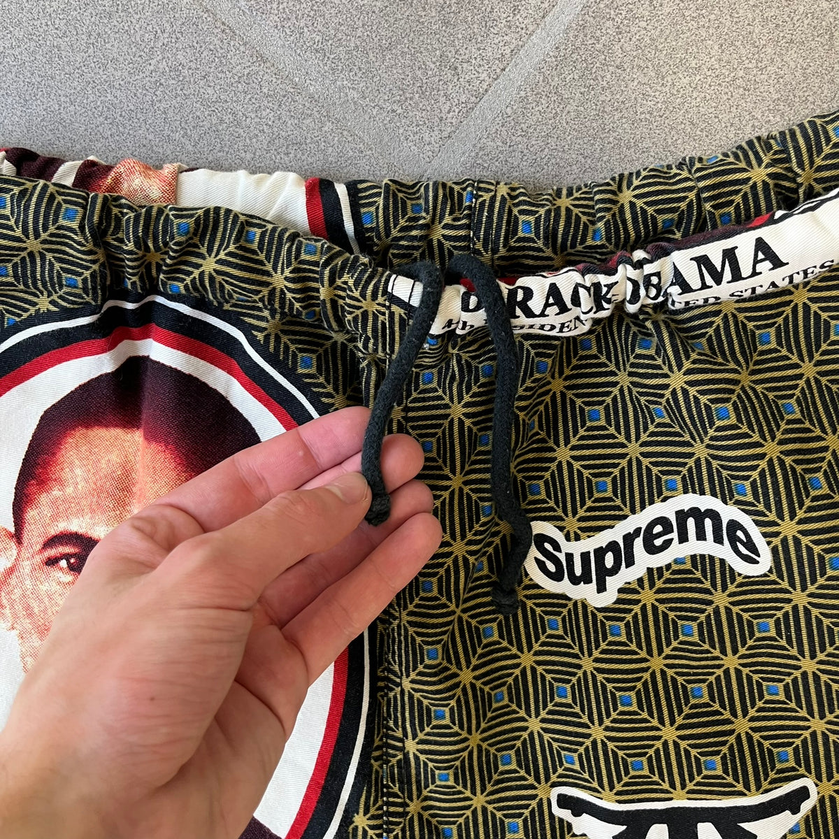 Supreme SS2017 Obama Green Pants are green/olive pants with the all-over patchwork print incorporating Barack Obama’s face, the words “Barack Obama,” and scattered Supreme logos. The design pays homage to the “khanas,” vibrant patterned garments with political graphics made by local designers in Ghana to commemorate the former president’s 2009 visit. They have two front pockets and one back pocket.