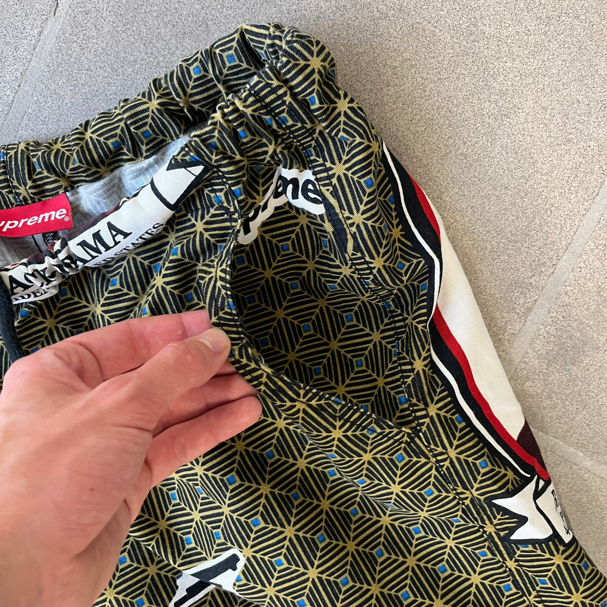 Supreme SS2017 Obama Green Pants are green/olive pants with the all-over patchwork print incorporating Barack Obama’s face, the words “Barack Obama,” and scattered Supreme logos. The design pays homage to the “khanas,” vibrant patterned garments with political graphics made by local designers in Ghana to commemorate the former president’s 2009 visit. They have two front pockets and one back pocket.