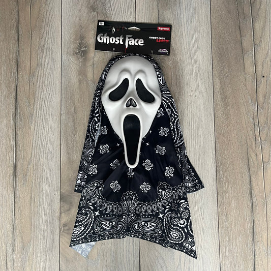 Supreme SS26 Ghostface Mask is a PVC face mask released on April 30, 2026, as part of the Spring/Summer 2026 collection. The mask features the classic white Ghostface design, combined with a black fabric hood element covered in white bandana-style patterns and integrated Supreme tags. Additional hanging strips on the sides enhance the hooded visual effect.