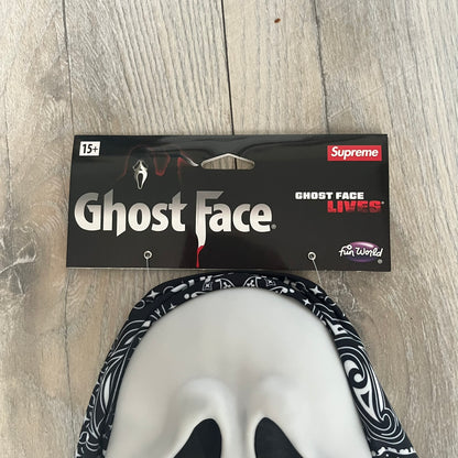 Supreme SS26 Ghostface Mask is a PVC face mask released on April 30, 2026, as part of the Spring/Summer 2026 collection. The mask features the classic white Ghostface design, combined with a black fabric hood element covered in white bandana-style patterns and integrated Supreme tags. Additional hanging strips on the sides enhance the hooded visual effect.