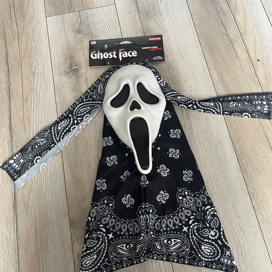 Supreme SS26 Ghostface Mask is a PVC face mask released on April 30, 2026, as part of the Spring/Summer 2026 collection. The mask features the classic white Ghostface design, combined with a black fabric hood element covered in white bandana-style patterns and integrated Supreme tags. Additional hanging strips on the sides enhance the hooded visual effect.