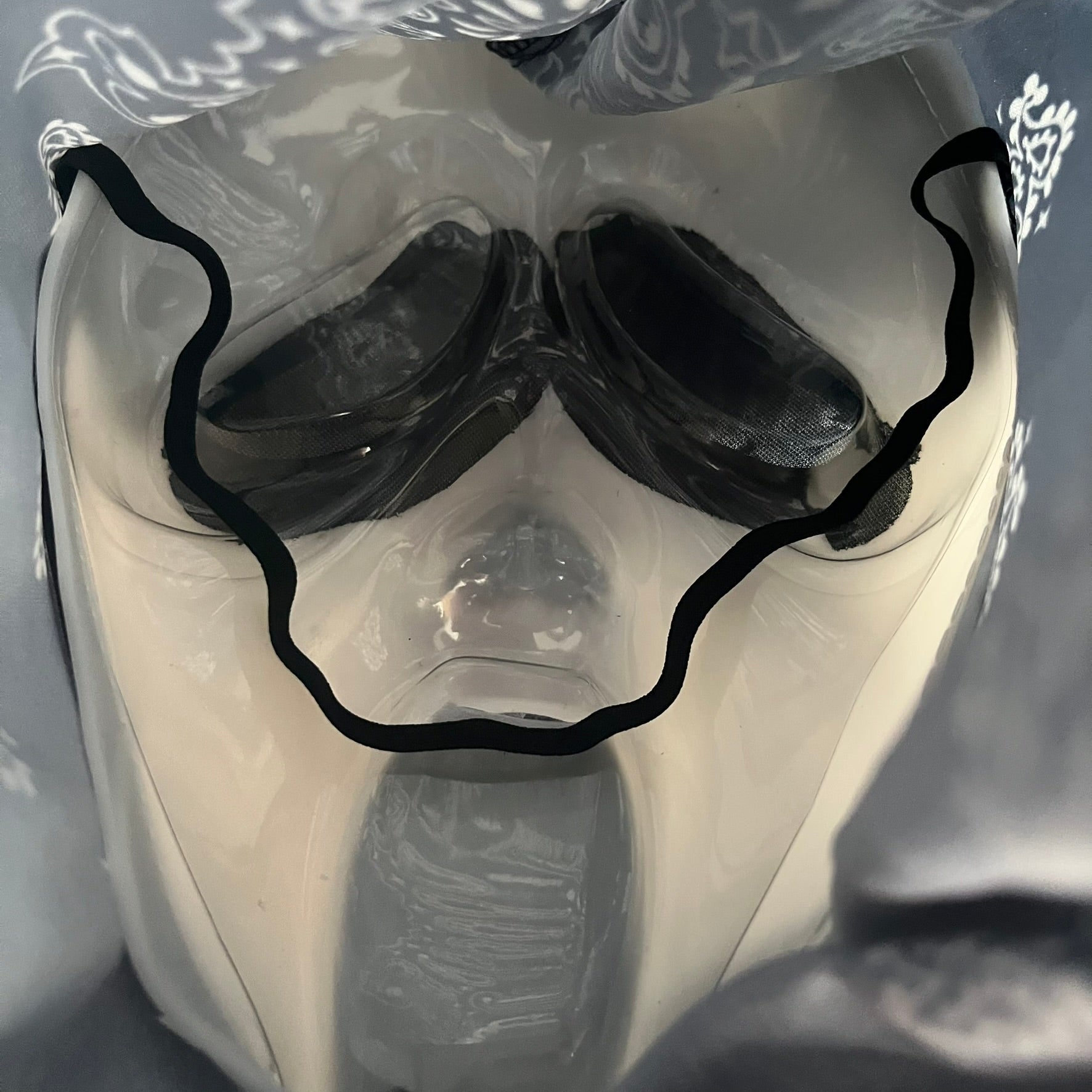 Supreme SS26 Ghostface Mask is a PVC face mask released on April 30, 2026, as part of the Spring/Summer 2026 collection. The mask features the classic white Ghostface design, combined with a black fabric hood element covered in white bandana-style patterns and integrated Supreme tags. Additional hanging strips on the sides enhance the hooded visual effect.
