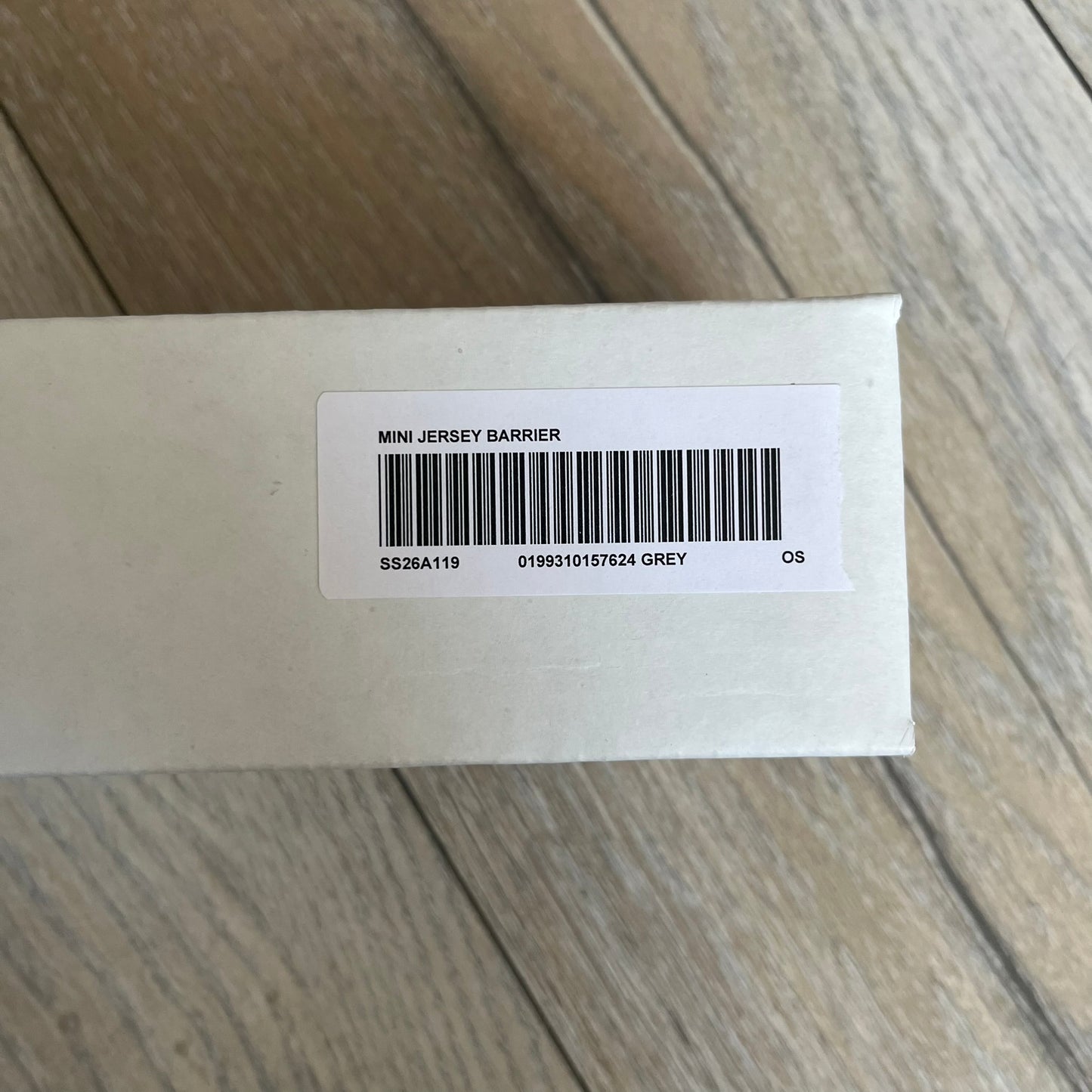 Supreme SS26 Mini Materials 1:12 Scale Jersey Barrier is a grey miniature accessory released on March 26, 2026, as part of the Spring/Summer 2026 collection. The piece replicates a standard jersey barrier in 1:12 scale with realistic construction-style detailing. This item was produced as part of Supreme’s Mini Materials accessory line.