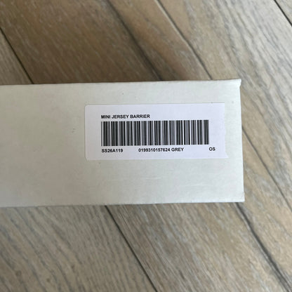 Supreme SS26 Mini Materials 1:12 Scale Jersey Barrier is a grey miniature accessory released on March 26, 2026, as part of the Spring/Summer 2026 collection. The piece replicates a standard jersey barrier in 1:12 scale with realistic construction-style detailing. This item was produced as part of Supreme’s Mini Materials accessory line.