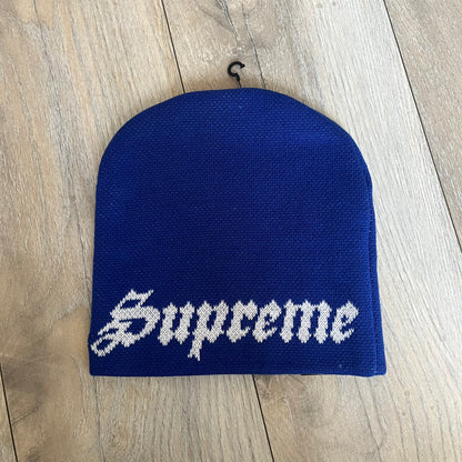 Supreme SS26 New Era Ghostface Black Beanie is a Royal (Blue) knit beanie released on March 26, 2026, as part of the Spring/Summer 2026 collection. The front features a white and black Ghostface graphic, while the back includes “Supreme” text in a gothic-style font, with a small New Era logo embroidered on the side. The beanie is constructed from knit fabric for warmth and everyday wear.