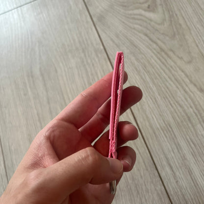  Supreme SS26 Webbing Keychain is a pink keychain from the Spring/Summer 2026 collection. It features a silver-tone 1-inch keyring and a pink rubber Supreme box logo patch attached to the front. The reverse side is plain with no additional graphics.