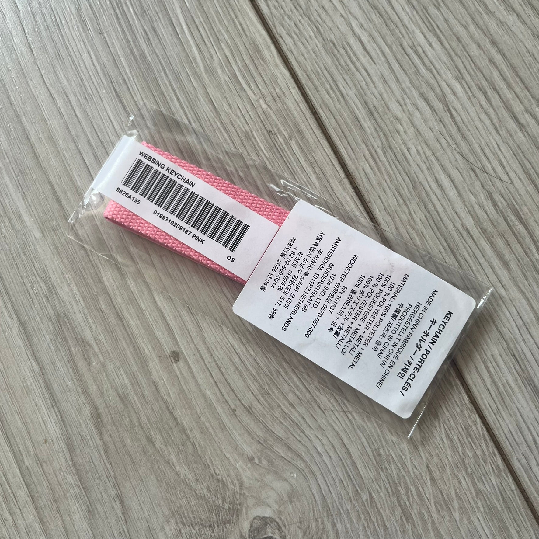  Supreme SS26 Webbing Keychain is a pink keychain from the Spring/Summer 2026 collection. It features a silver-tone 1-inch keyring and a pink rubber Supreme box logo patch attached to the front. The reverse side is plain with no additional graphics.
