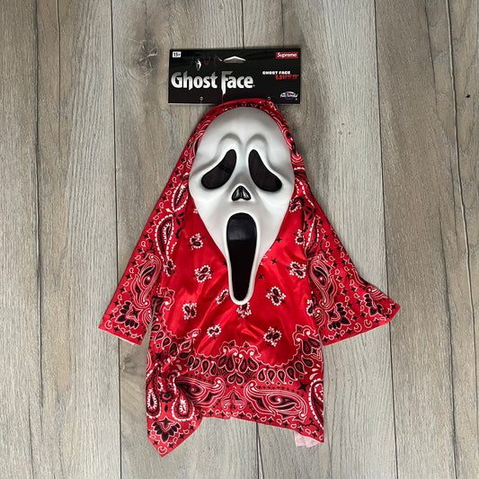 Supreme SS26 Ghostface Mask is a PVC face mask released on April 30, 2026, as part of the Spring/Summer 2026 collection. The mask features the classic white Ghostface design, combined with a red fabric hood element covered in white and black bandana-style patterns and integrated Supreme tags. Additional hanging strips on the sides enhance the hooded visual effect.