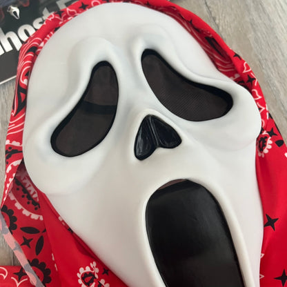 Supreme SS26 Ghostface Mask is a PVC face mask released on April 30, 2026, as part of the Spring/Summer 2026 collection. The mask features the classic white Ghostface design, combined with a red fabric hood element covered in white and black bandana-style patterns and integrated Supreme tags. Additional hanging strips on the sides enhance the hooded visual effect.