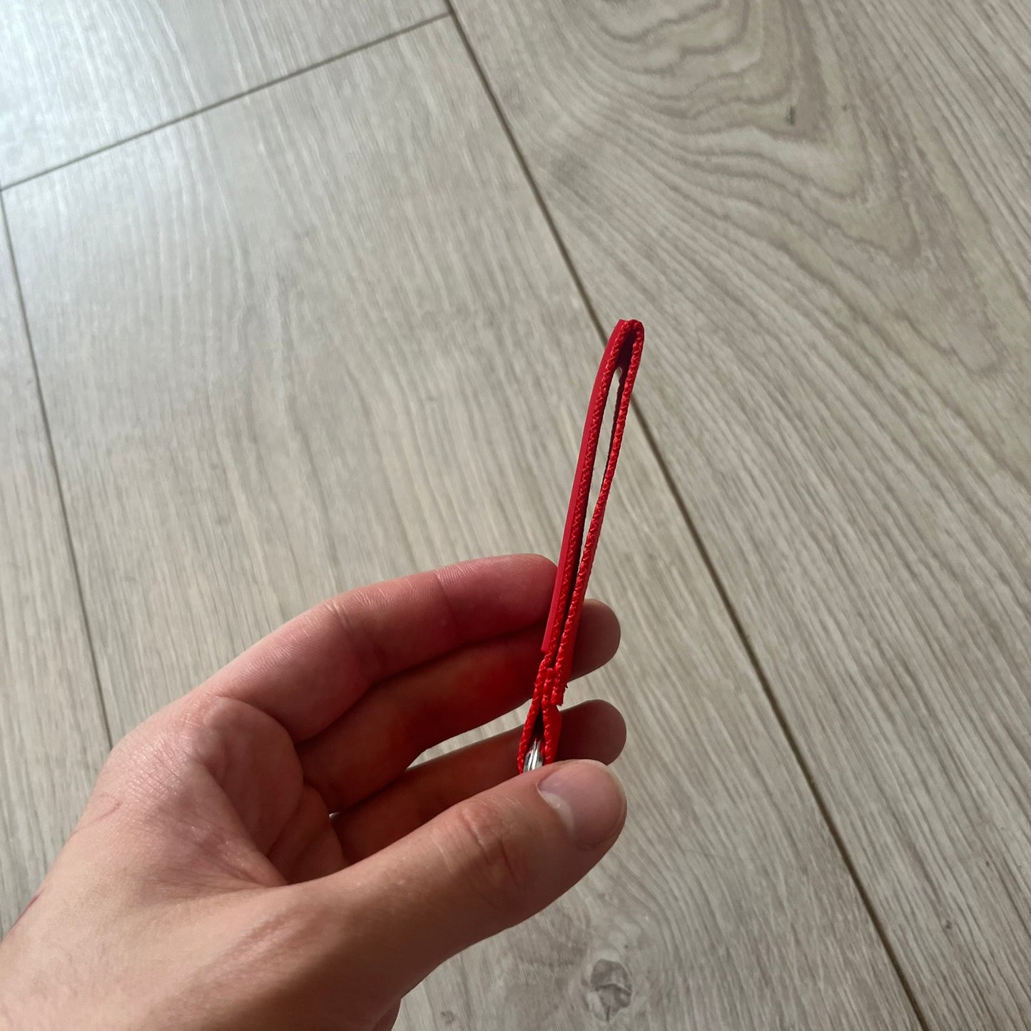 Supreme SS26 Webbing Keychain is a red keychain from the Spring/Summer 2026 collection. It features a silver-tone 1-inch keyring and a red rubber Supreme box logo patch attached to the front. The reverse side is plain with no additional graphics.