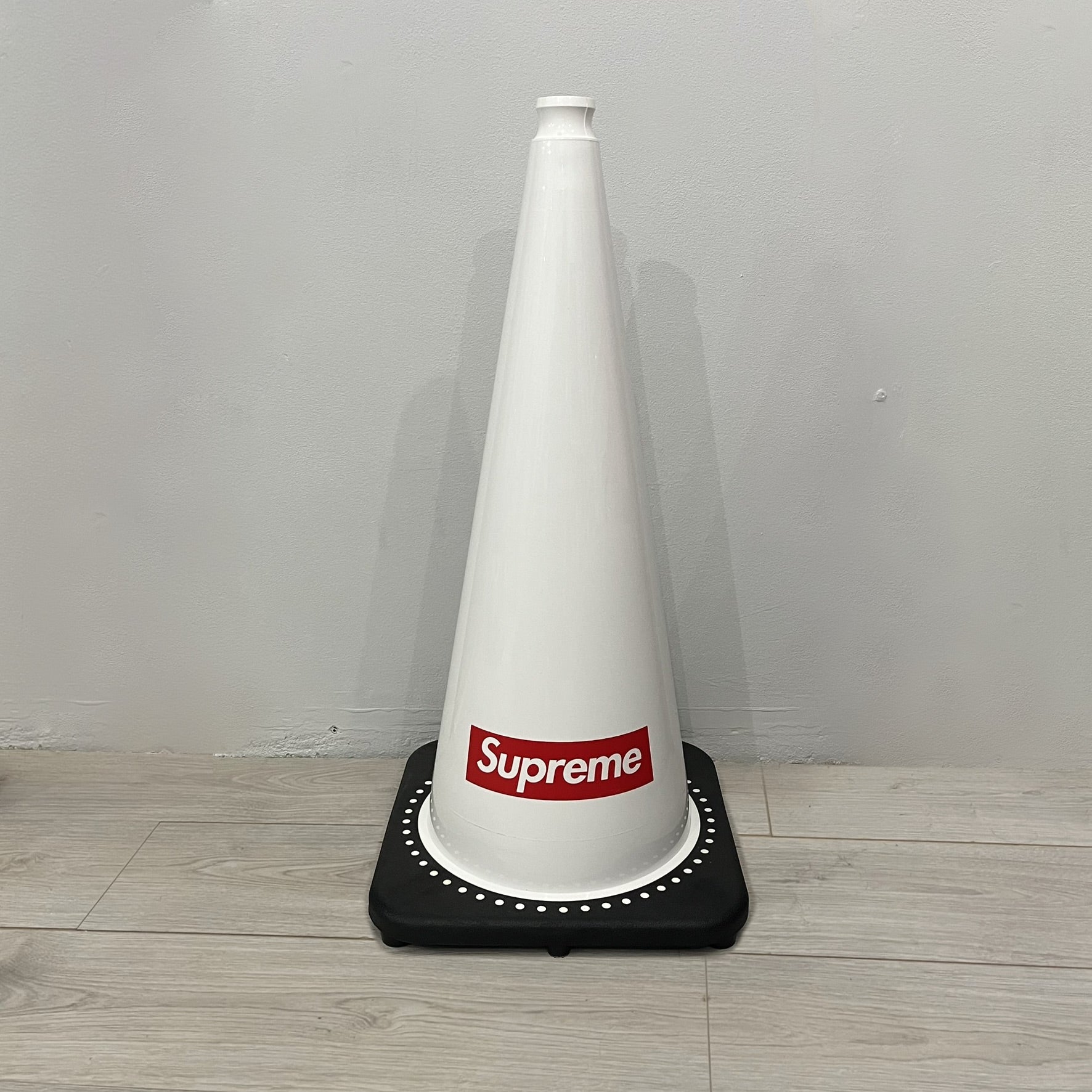 The Supreme Traffic Cone FW25 White features a clean white PVC body with a classic red Supreme box logo on the lower front. Designed for display purposes only, it sits on a black base and is not intended for use as a functional traffic marker. Released on October 16, 2025.
