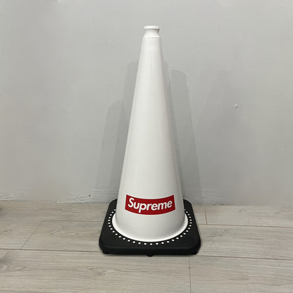 The Supreme Traffic Cone FW25 White features a clean white PVC body with a classic red Supreme box logo on the lower front. Designed for display purposes only, it sits on a black base and is not intended for use as a functional traffic marker. Released on October 16, 2025.