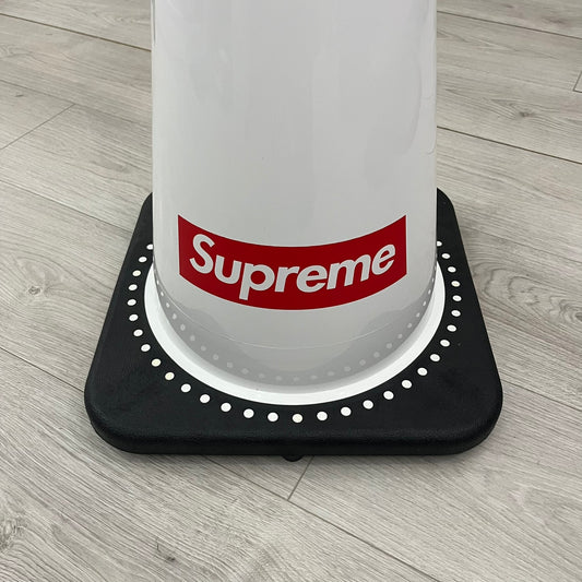 The Supreme Traffic Cone FW25 White features a clean white PVC body with a classic red Supreme box logo on the lower front. Designed for display purposes only, it sits on a black base and is not intended for use as a functional traffic marker. Released on October 16, 2025.