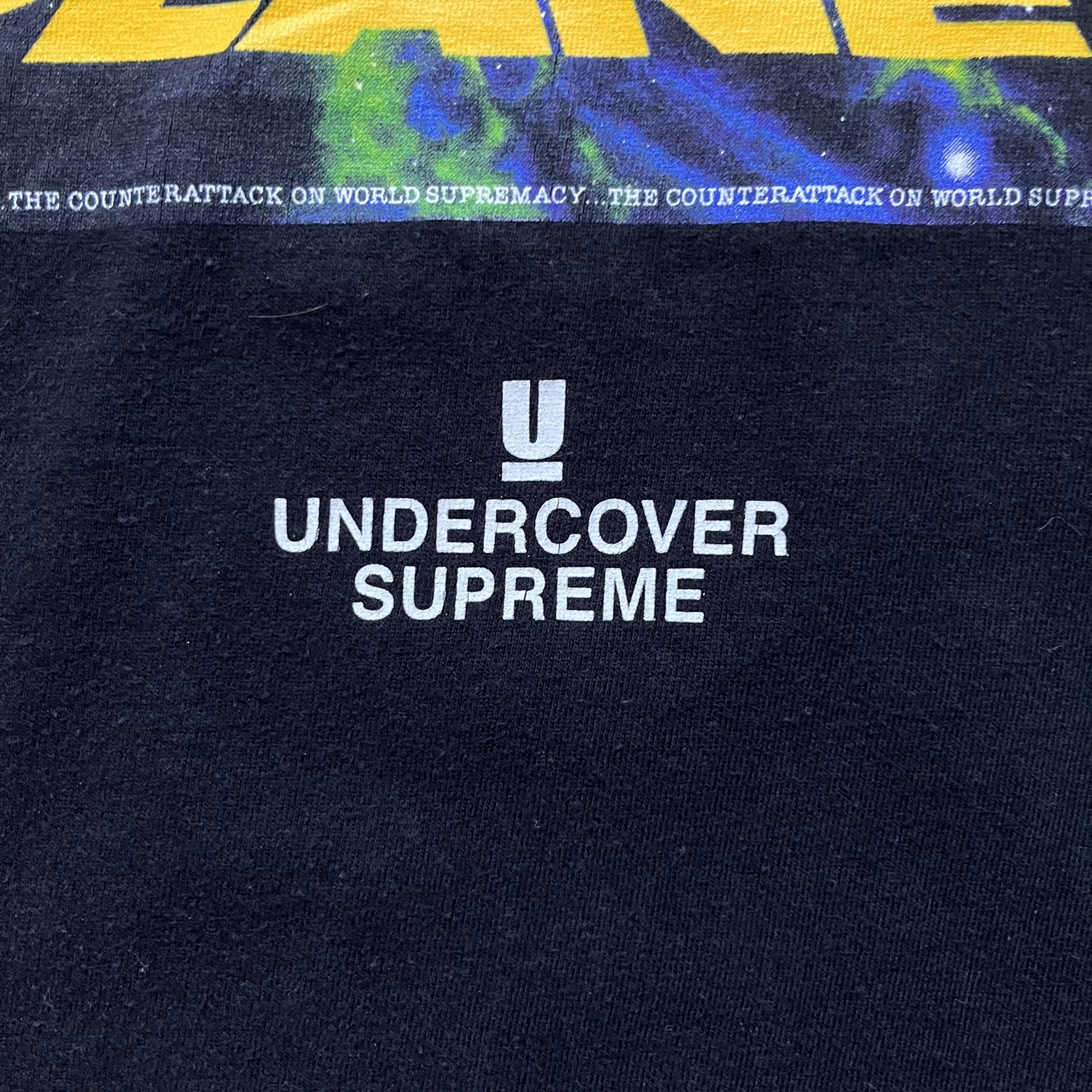 Supreme Undercover Public Enemy Counterattack SS18 Longsleeve Tee is a black long-sleeve T-shirt released on March 15, 2018, crafted from 100% cotton. The front features white “The Counterattack On World Supremacy” text with a small Supreme UNDERCOVER logo beneath, while the back displays a large Public Enemy “Fear of a Black Planet” graphic with galaxy and planet imagery and the same co-branded logo below. The design includes a ribbed crewneck and ribbed cuffs, reflecting the SS18 collaboration between Sup
