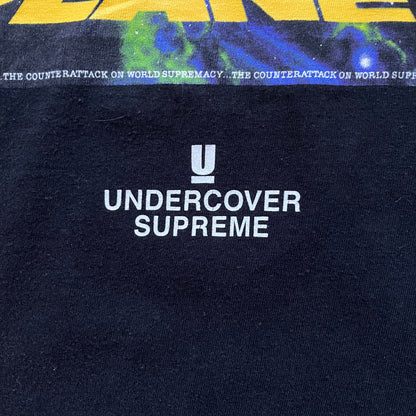 Supreme Undercover Public Enemy Counterattack SS18 Longsleeve Tee is a black long-sleeve T-shirt released on March 15, 2018, crafted from 100% cotton. The front features white “The Counterattack On World Supremacy” text with a small Supreme UNDERCOVER logo beneath, while the back displays a large Public Enemy “Fear of a Black Planet” graphic with galaxy and planet imagery and the same co-branded logo below. The design includes a ribbed crewneck and ribbed cuffs, reflecting the SS18 collaboration between Sup