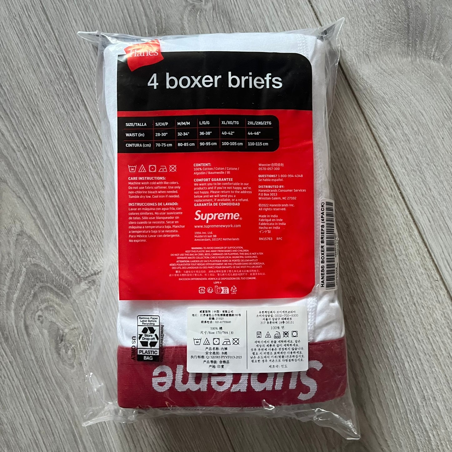 Supreme x Hanes white boxer briefs made of cotton with a stretch fit. Features a red elastic waistband with white Supreme logo text in Futura Oblique font. Classic Hanes base model with co-branded detailing.