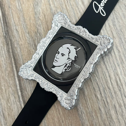 Swatch x Jeremy Scott 2011 Portrait Analog Watch SUOZ121 is an analog watch from the designer’s second collaboration with Swatch, featuring a portrait of Jeremy Scott on the dial and his signature on the strap. The watch includes a silver-tone ornate removable frame, black dial with fixed bezel, and Swiss-made quartz movement. It is water resistant up to 30 meters, comes with original packaging, and retains protective film, with the hour hand partially obscured by the portrait design.