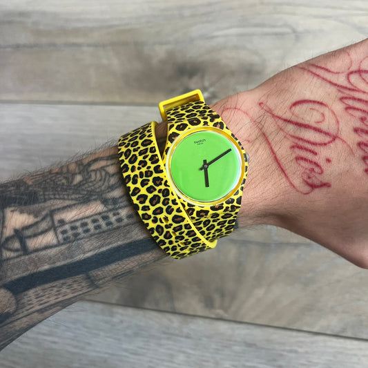 Swatch x Jeremy Scott 2011 Punk Analog Watch GZ251 is a quartz watch from the Gent Original line featuring a bright green dial with black hands and a plastic case. The design includes a comically long silicone strap with leopard print that wraps twice around the wrist, secured with multiple yellow loops, and Jeremy Scott branding on the upper strap. The watch is water resistant to 3 bar and comes with original box and papers