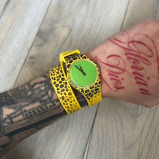 Swatch x Jeremy Scott 2011 Punk Analog Watch GZ251 is a quartz watch from the Gent Original line featuring a bright green dial with black hands and a plastic case. The design includes a comically long silicone strap with leopard print that wraps twice around the wrist, secured with multiple yellow loops, and Jeremy Scott branding on the upper strap. The watch is water resistant to 3 bar and comes with original box and papers.