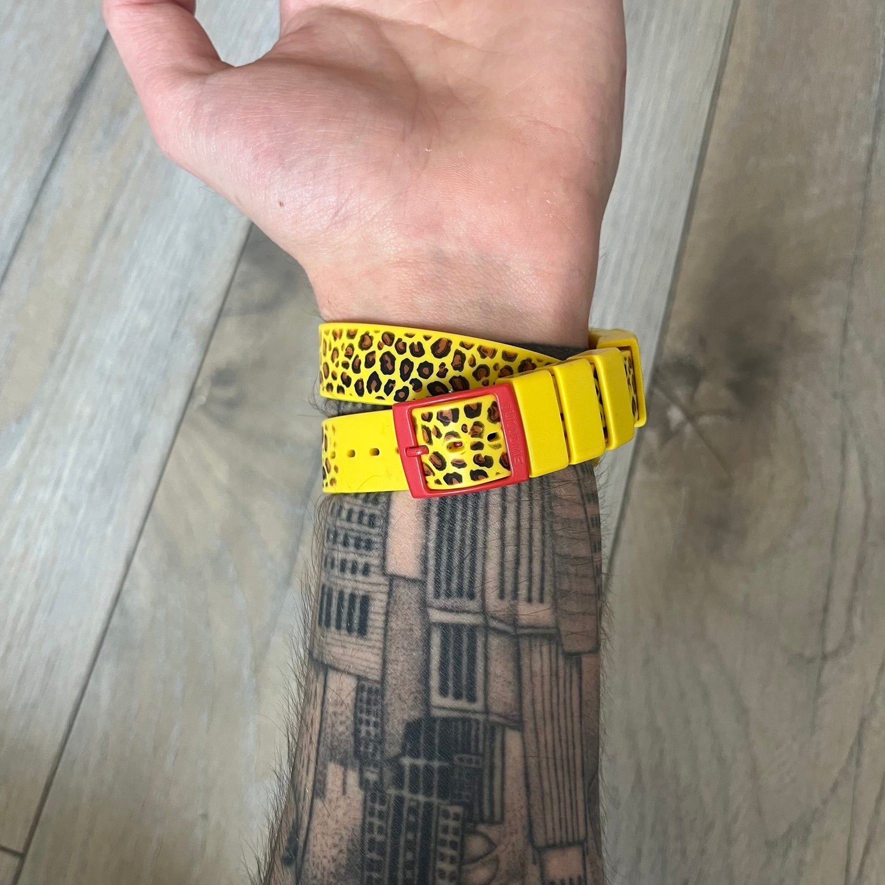 Swatch x Jeremy Scott 2011 Punk Analog Watch GZ251 is a quartz watch from the Gent Original line featuring a bright green dial with black hands and a plastic case. The design includes a comically long silicone strap with leopard print that wraps twice around the wrist, secured with multiple yellow loops, and Jeremy Scott branding on the upper strap. The watch is water resistant to 3 bar and comes with original box and papers.