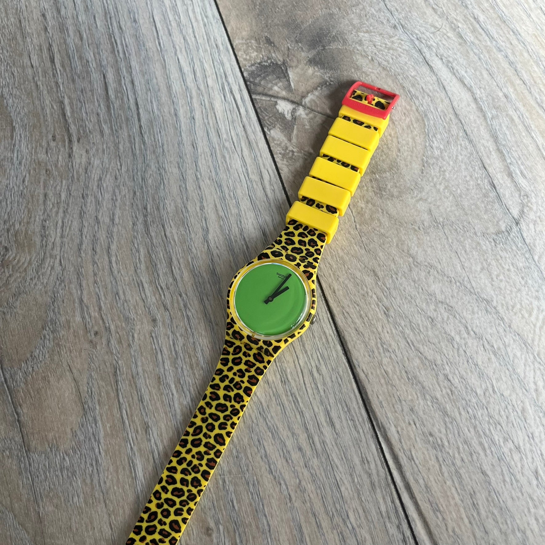 Swatch x Jeremy Scott 2011 Punk Analog Watch GZ251 is a quartz watch from the Gent Original line featuring a bright green dial with black hands and a plastic case. The design includes a comically long silicone strap with leopard print that wraps twice around the wrist, secured with multiple yellow loops, and Jeremy Scott branding on the upper strap. The watch is water resistant to 3 bar and comes with original box and papers