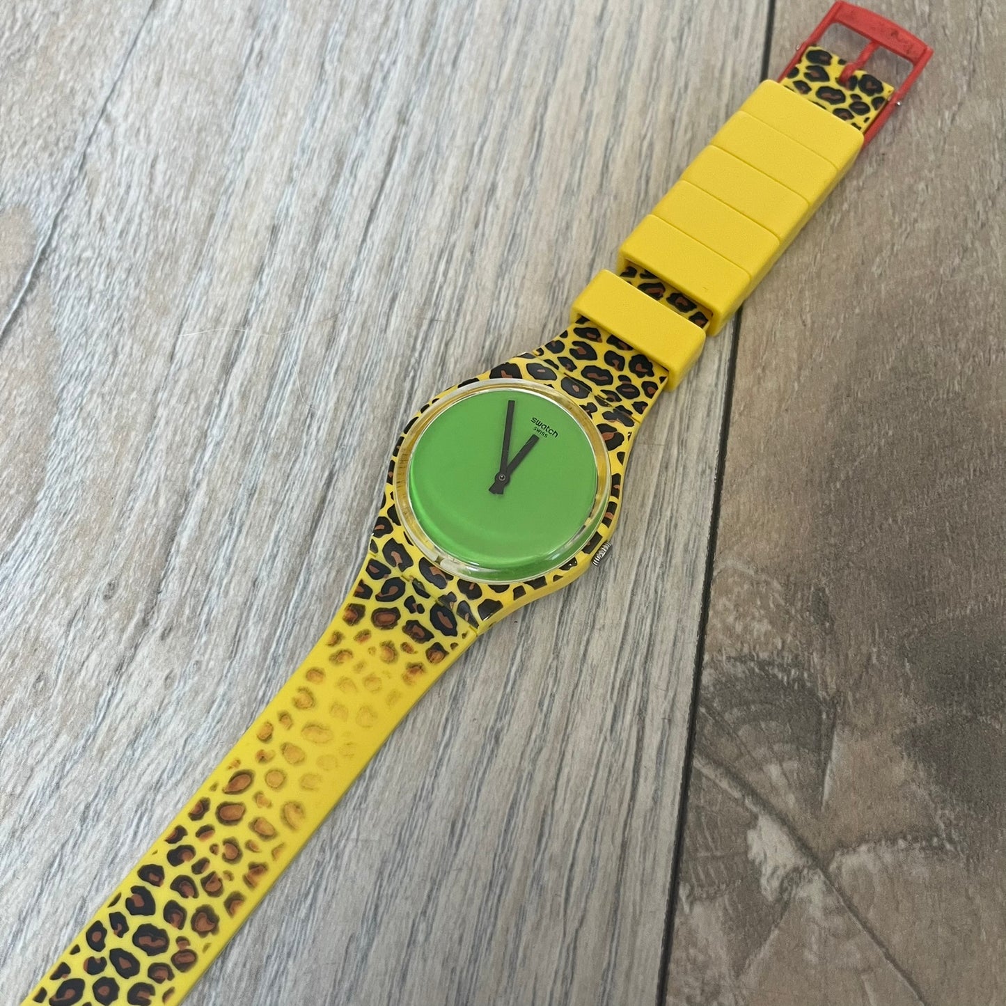 Swatch x Jeremy Scott 2011 Punk Analog Watch GZ251 is a quartz watch from the Gent Original line featuring a bright green dial with black hands and a plastic case. The design includes a comically long silicone strap with leopard print that wraps twice around the wrist, secured with multiple yellow loops, and Jeremy Scott branding on the upper strap. The watch is water resistant to 3 bar and comes with original box and papers.