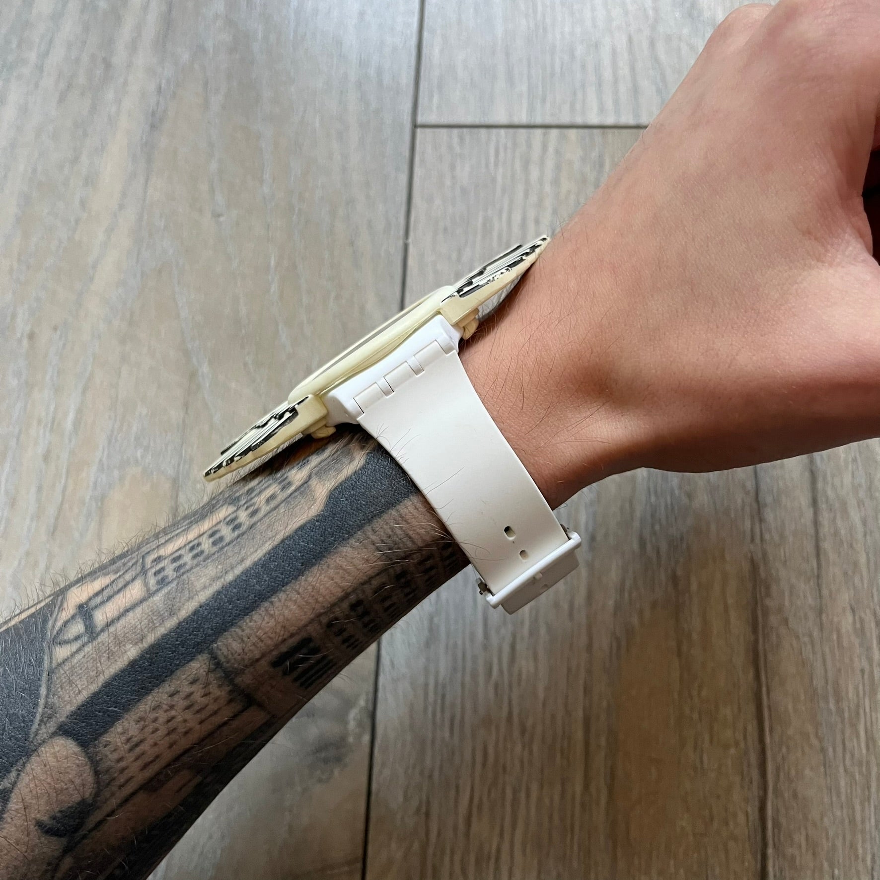 Swatch x Jeremy Scott SUOZ103 “Wings” analog watch released in 2011 as part of Jeremy Scott’s collaboration with Swatch. The watch features a 41 mm case, white dial with Swatch text, black hands, and a white silicone strap. The design includes removable clip-on white 3D wings with black detailing, Swiss quartz movement, patented Swatch battery system, water resistance, and Jeremy Scott branding on the caseback.