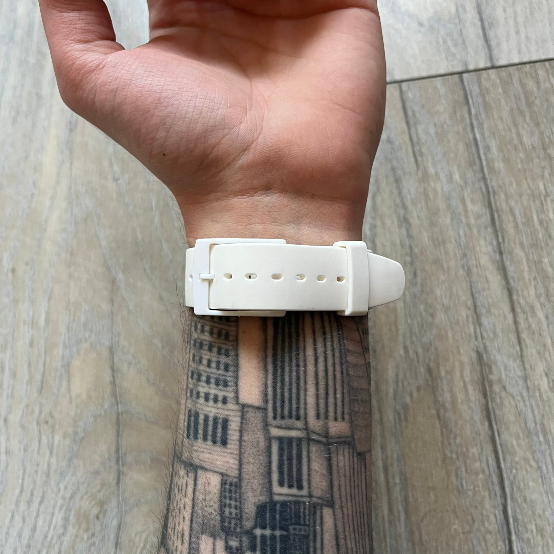 Swatch x Jeremy Scott SUOZ103 “Wings” analog watch released in 2011 as part of Jeremy Scott’s collaboration with Swatch. The watch features a 41 mm case, white dial with Swatch text, black hands, and a white silicone strap. The design includes removable clip-on white 3D wings with black detailing, Swiss quartz movement, patented Swatch battery system, water resistance, and Jeremy Scott branding on the caseback.