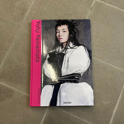 Taschen *Yohji Yamamoto* Hardcover Book is a hardcover publication curated by Terry Jones, exploring the groundbreaking work and career of Yohji Yamamoto. The 120-page book features photography, biographical content, and rare visuals drawn from more than 30 years of i-D magazine archives, along with personal insights into the designer’s work and influence.
