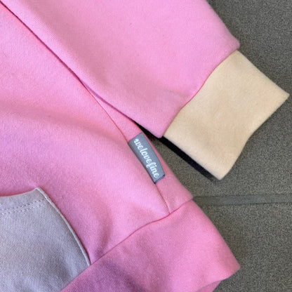 Team Fortress 2 Balloonicorn 2015 WeLoveFine Zip-Up Hoodie is a bright pink unisex colorblock hoodie from Valve’s Team Fortress 2 line, with a detailed 3D plush Balloonicorn hood featuring embroidered eyes, a 3D horn, nose, and ears. It has front pockets, a custom metal Balloonicorn cameo zipper pull, and a light blue printed saddle graphic that wraps from the back to the front. The licensed TF2 neck tag carries 2015 and We Love Fine branding. Super rare.