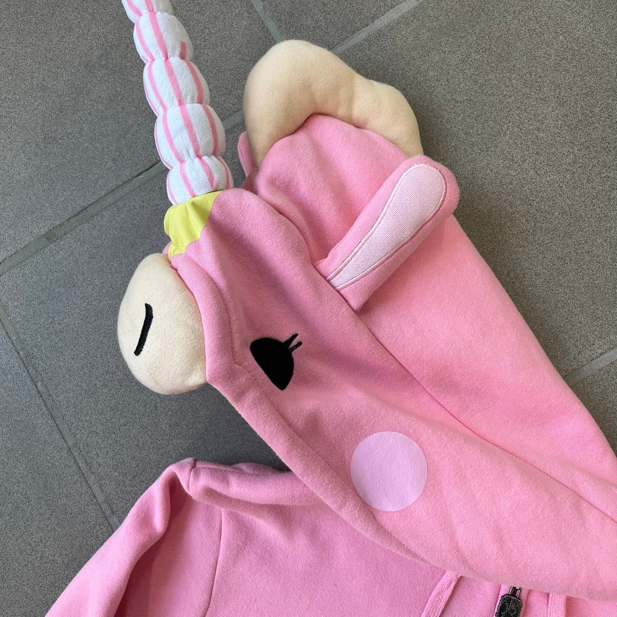 Team Fortress 2 Balloonicorn 2015 WeLoveFine Zip-Up Hoodie is a bright pink unisex colorblock hoodie from Valve’s Team Fortress 2 line, with a detailed 3D plush Balloonicorn hood featuring embroidered eyes, a 3D horn, nose, and ears. It has front pockets, a custom metal Balloonicorn cameo zipper pull, and a light blue printed saddle graphic that wraps from the back to the front. The licensed TF2 neck tag carries 2015 and We Love Fine branding. Super rare.
