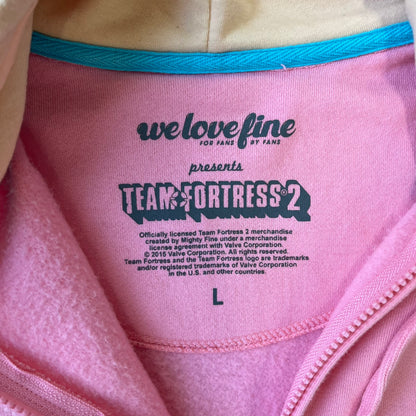 Team Fortress 2 Balloonicorn 2015 WeLoveFine Zip-Up Hoodie is a bright pink unisex colorblock hoodie from Valve’s Team Fortress 2 line, with a detailed 3D plush Balloonicorn hood featuring embroidered eyes, a 3D horn, nose, and ears. It has front pockets, a custom metal Balloonicorn cameo zipper pull, and a light blue printed saddle graphic that wraps from the back to the front. The licensed TF2 neck tag carries 2015 and We Love Fine branding. Super rare.