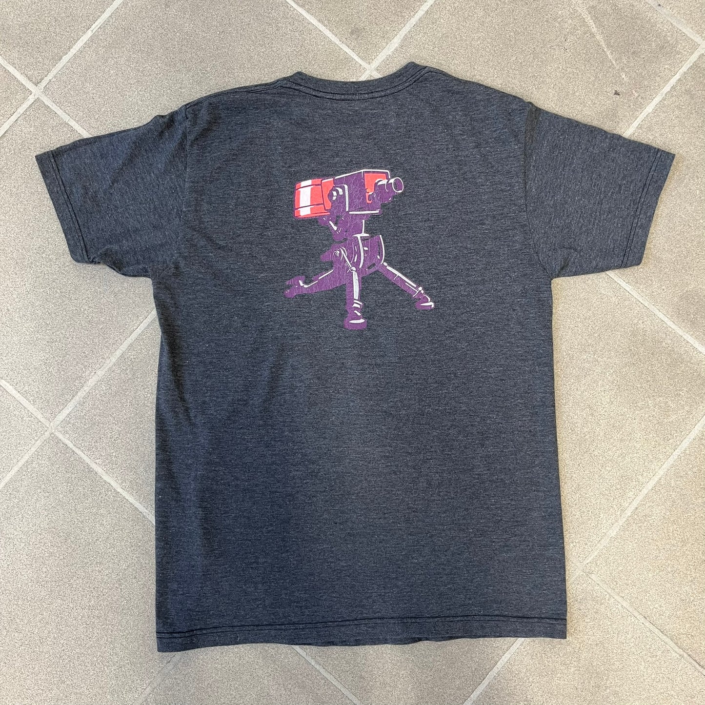 Team Fortress 2 “Balloonicorn & Sentry” 2010s Tee is a dark grey cotton-polyester blend T-shirt with a printed Valve neck tag. The front features a pink Balloonicorn graphic, while the back displays a red Engineer Sentry graphic. This officially licensed Team Fortress 2 T-shirt is a rare release.
