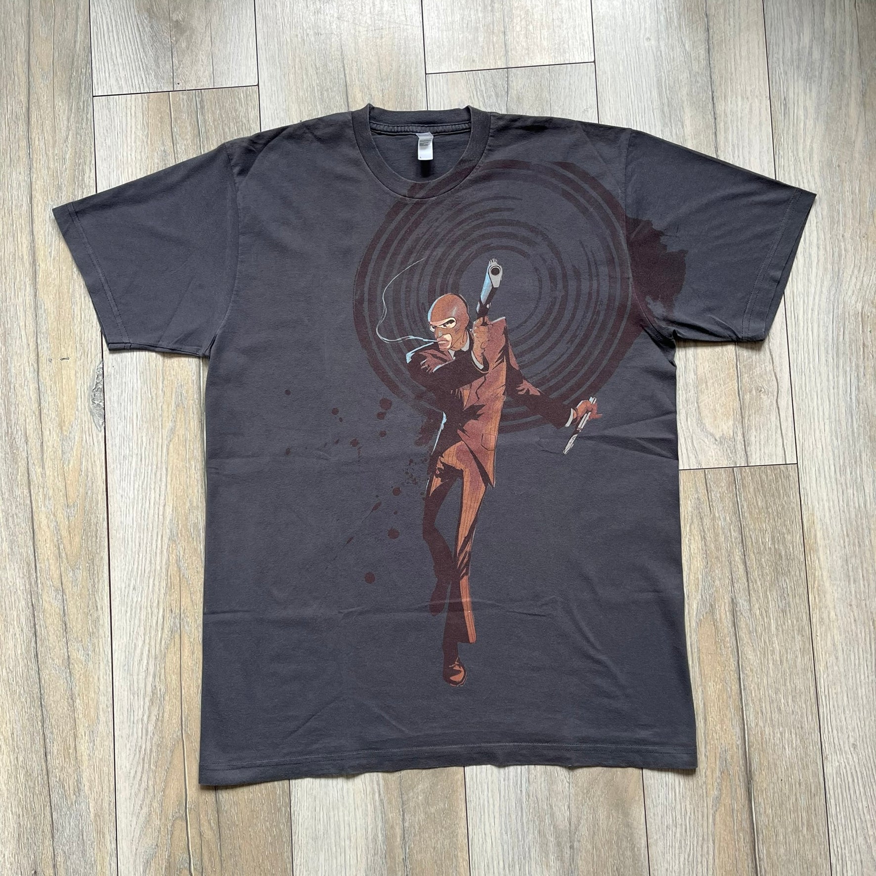 The Team Fortress 2 Red Spy 2010's Gray Tee is an official Valve shirt from the Sniper vs. Spy update, produced during Valve’s Amercian Apparel merch era. This charcoal gray tee features a red Spy character holding a butterfly knife and gun, set against a dark red target graphic with dripping effects. A super rare collectible, it represents one of the original Valve Store releases from over a decade ago.
